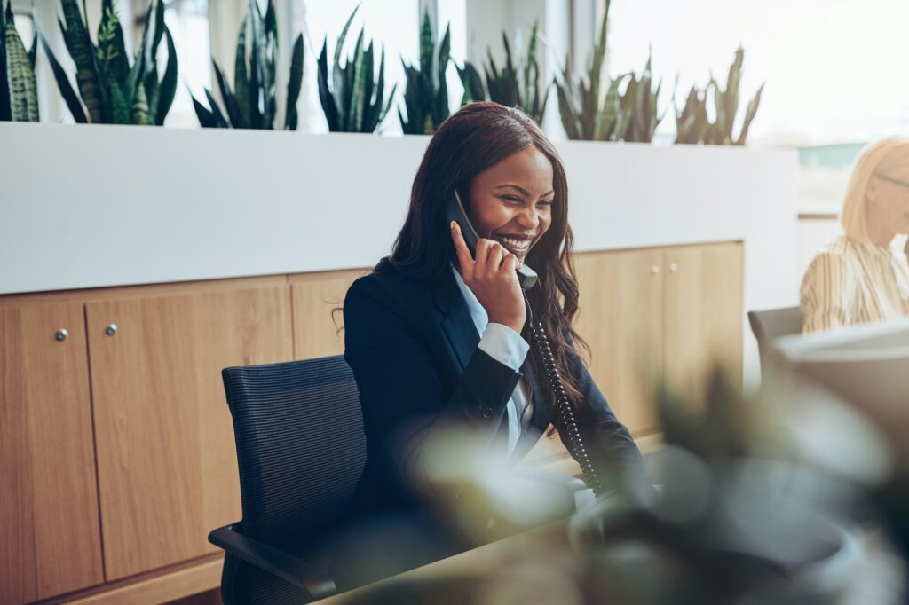 African American businesswomen talking on an office telephone and laughing